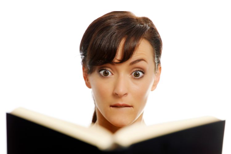 Woman reading book lookiong surprised